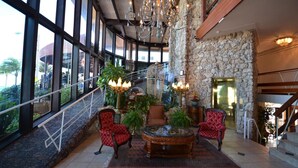 A spacious lobby with a stone wall, large windows, and a grand chandelier.