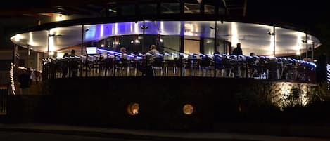 A waterfront restaurant with outdoor seating and a covered area.