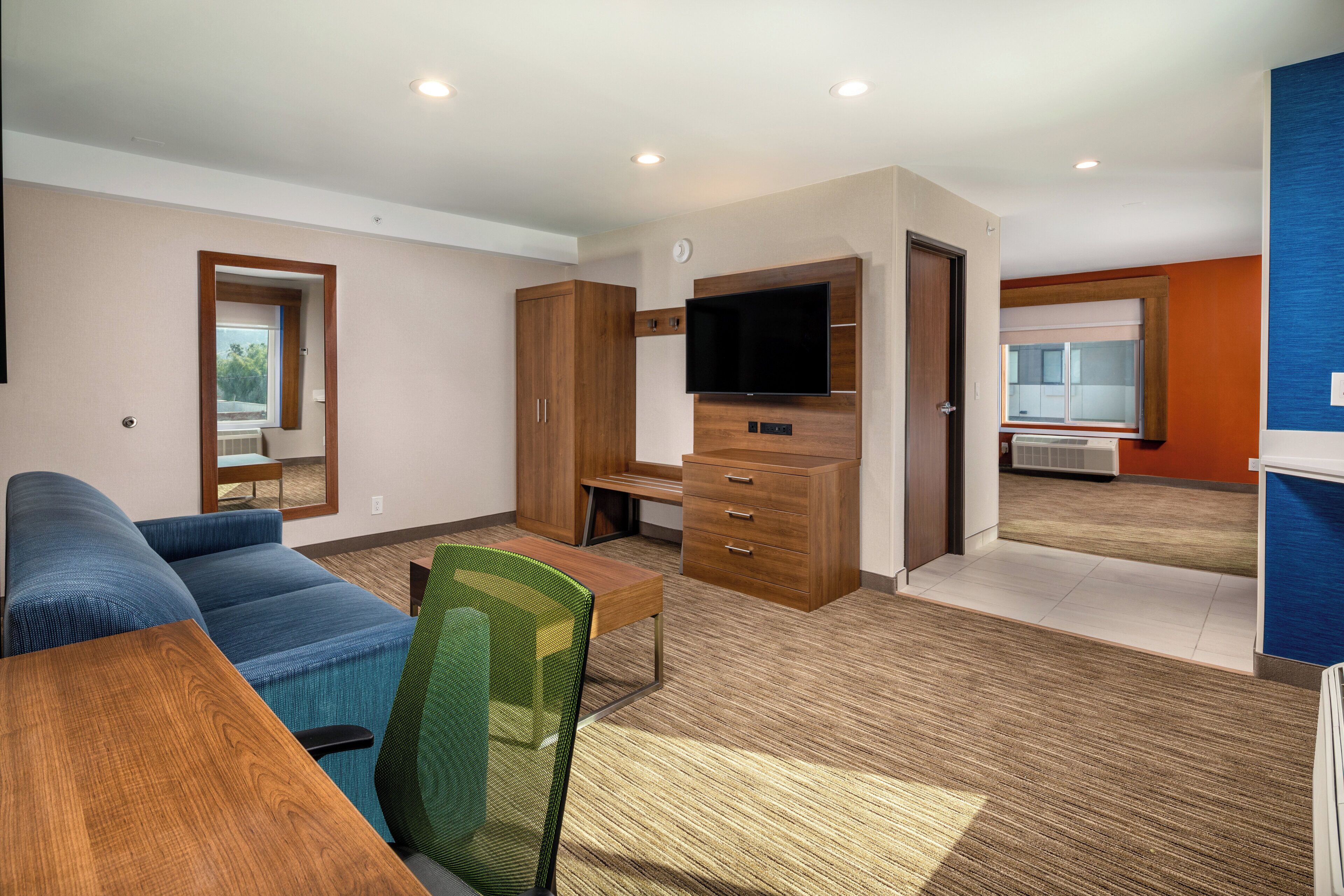 A modern living room with a sofa, a TV, and a kitchenette.