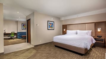 Habitación de hotel con una cama grande, un escritorio y una silla. Hay dos cuadros en la pared.