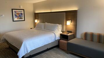 Een hotelkamer met een bed, nachtkastjes, een lamp, een bank en een aan de muur hangend kunstwerk.