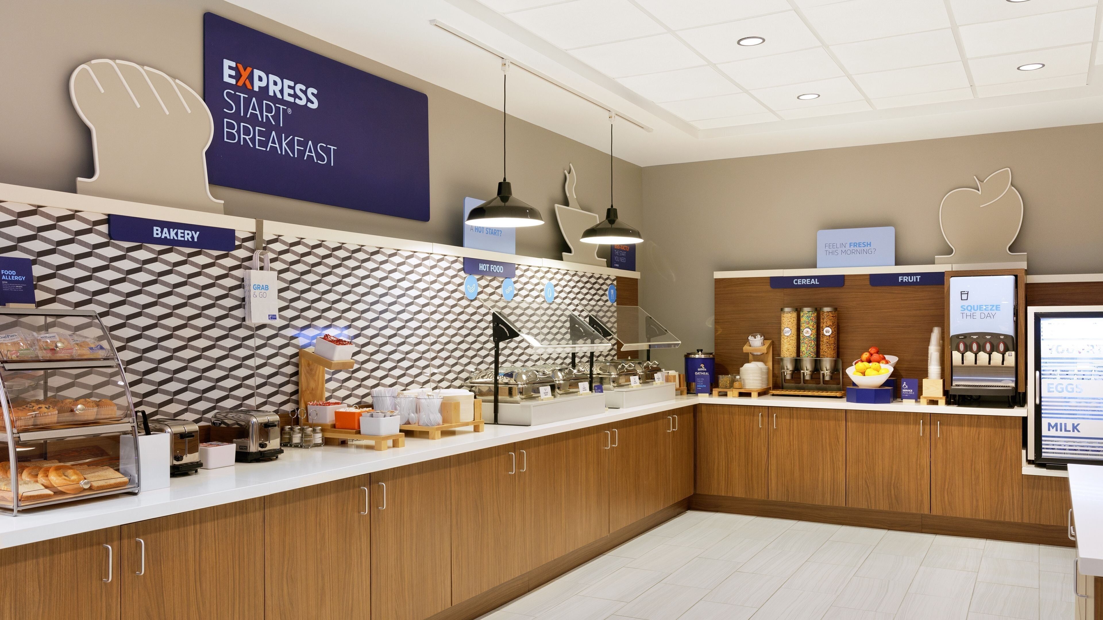 A breakfast area with labeled sections for bakery, hot food, cereal, fruit, and milk.