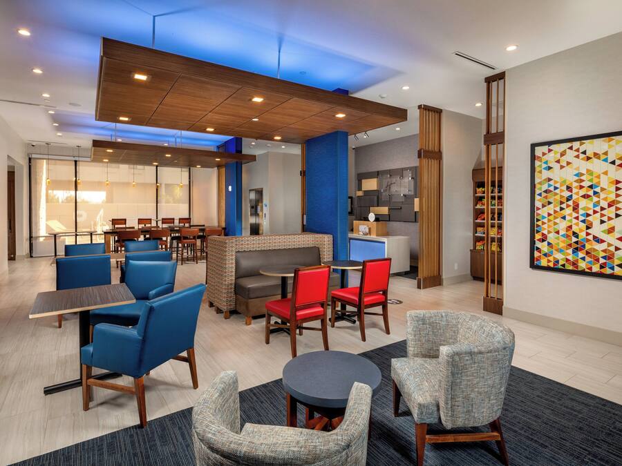 A modern hotel lobby with seating areas, a fireplace, and a colorful abstract painting.