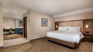A hotel room with a large bed, a desk with a chair, a sofa, and two wall-mounted light fixtures.