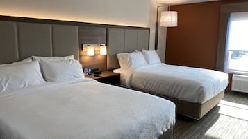 Een hotelkamer met twee bedden, een nachtkastje met een klok en een raam met uitzicht.