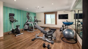 A gym with cardio machines, a bench press, dumbbells, and a large exercise ball. - Holiday Inn Express & Suites Chatsworth by IHG (Chatsworth)