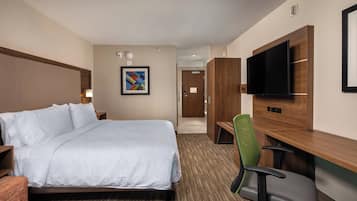 A hotel room with a bed, a desk, a chair, a television, and a framed picture on the wall.
