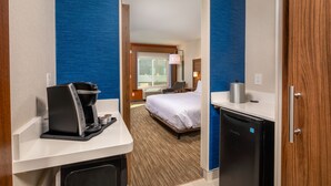 A hotel room with a bed, a coffee machine, a mini-fridge, and a desk with a lamp. - Holiday Inn Express & Suites Chatsworth by IHG (Chatsworth)