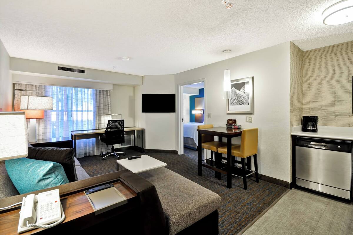 A hotel room with a living area, kitchenette, and a bed.