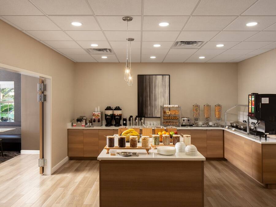 A modern kitchen with a central island, various food dispensers, and a coffee machine.