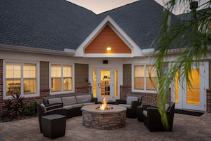 A patio area with a stone fire pit, outdoor furniture, and a brick exterior.