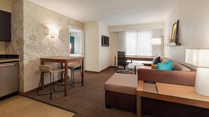 Habitación de hotel con kitchenette, comedor, sofá y televisor.