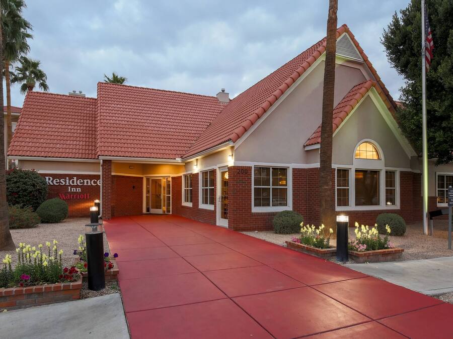 A brick building with a red roof and a red walkway leading to the entrance.