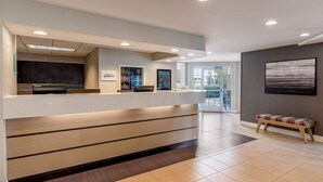 Un espace d’accueil comprenant un comptoir, un banc et donnant sur l’extérieur.