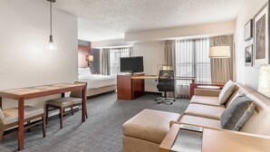 Une chambre d’hôtel avec un lit, un bureau, un canapé et une télévision.