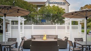 Un espace extérieur aménagé en terrasse, avec un foyer, des meubles en osier et des parasols.