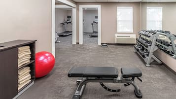 Una sala de gimnàstica amb equip d'exercici, una pilota vermella per a exercicis i una banca.