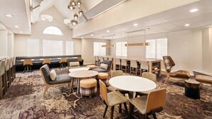 A spacious conference room with a high ceiling, large windows, and a variety of seating arrangements including round tables and a long bench. - Residence Inn by Marriott Scranton (Scranton)