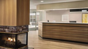 A modern hotel lobby with a wood-burning fireplace, a reception desk, and a large window offering a view of the outside. - Residence Inn by Marriott Scranton (Scranton)