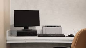 A modern office setup with a desktop computer, keyboard, and mouse on a white desk against a textured wall.