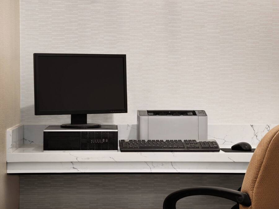 A modern office setup with a desktop computer, keyboard, and mouse on a white desk against a textured wall.