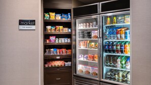 A refrigerated display case in a hotel lobby with snacks, beverages, and packaged foods.