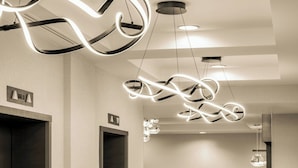 A modern lobby with a clean, minimalist design, featuring a central seating area with a blue rug, a wooden counter, and a unique ceiling light fixture. - Residence Inn by Marriott Washington, DC/Dupont Circle (Washington)