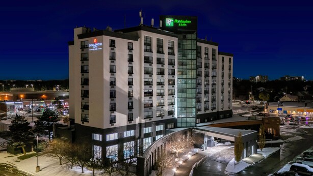Ein mehrstöckiges Hotel mit Holiday Inn Schild, das eine zentrale Glasfassade und mehrere Balkone aufweist.