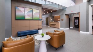 Eine moderne Hotellobby mit gewölbter Decke, einer Rezeption und einer Sitzecke mit Ledersesseln und einem kleinen Tisch.