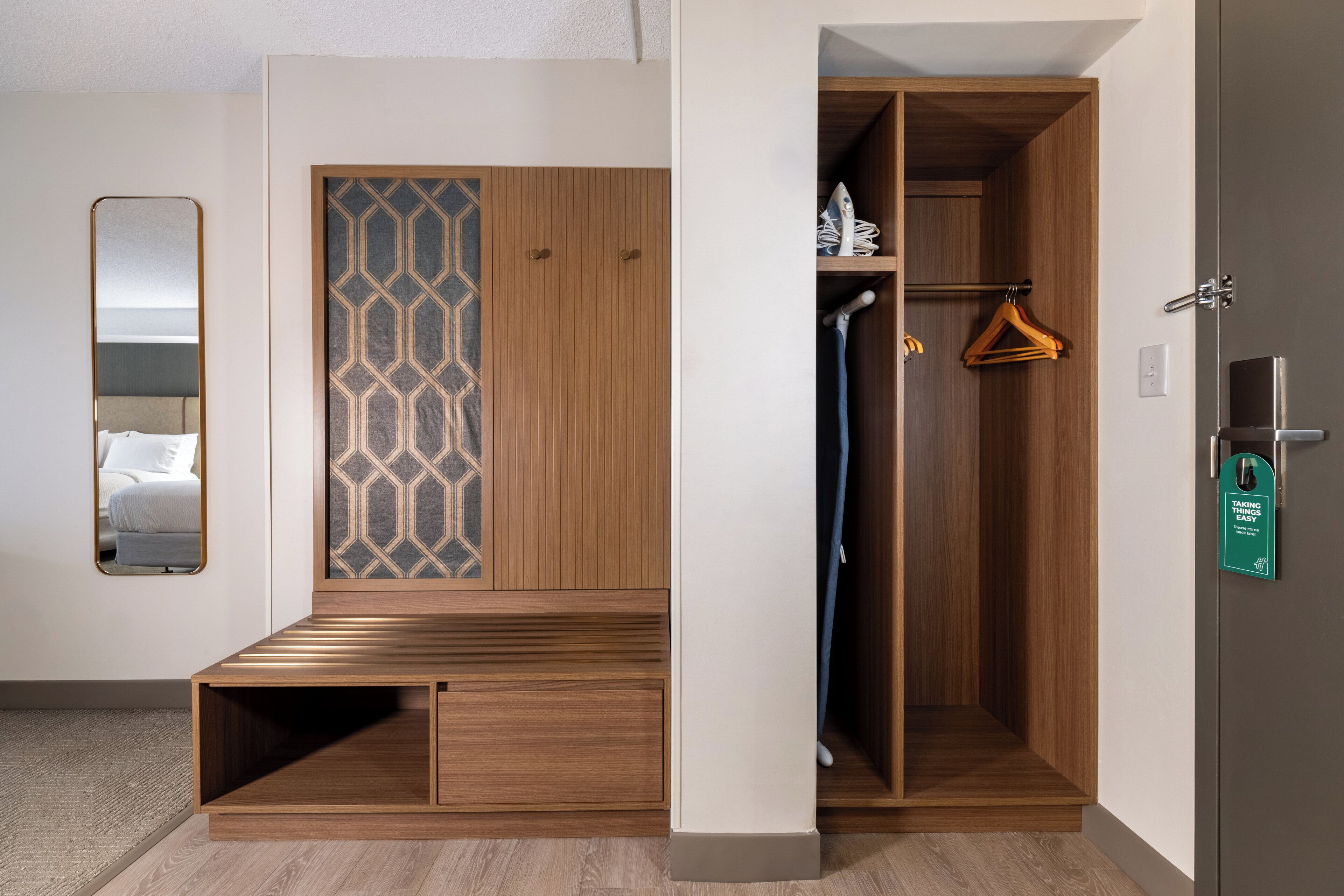 Un vestidor con puertas de madera, un espejo y una percha.