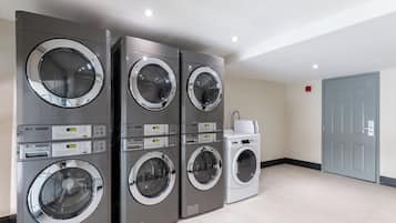 A laundry room with four stacked front-loading washing machines and a single top-loading machine.