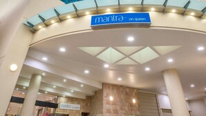 A hotel entrance with a sign reading 'mantra on queen' and a modern architectural design with a curved roof and columns. - Mantra on Queen (Brisbane)
