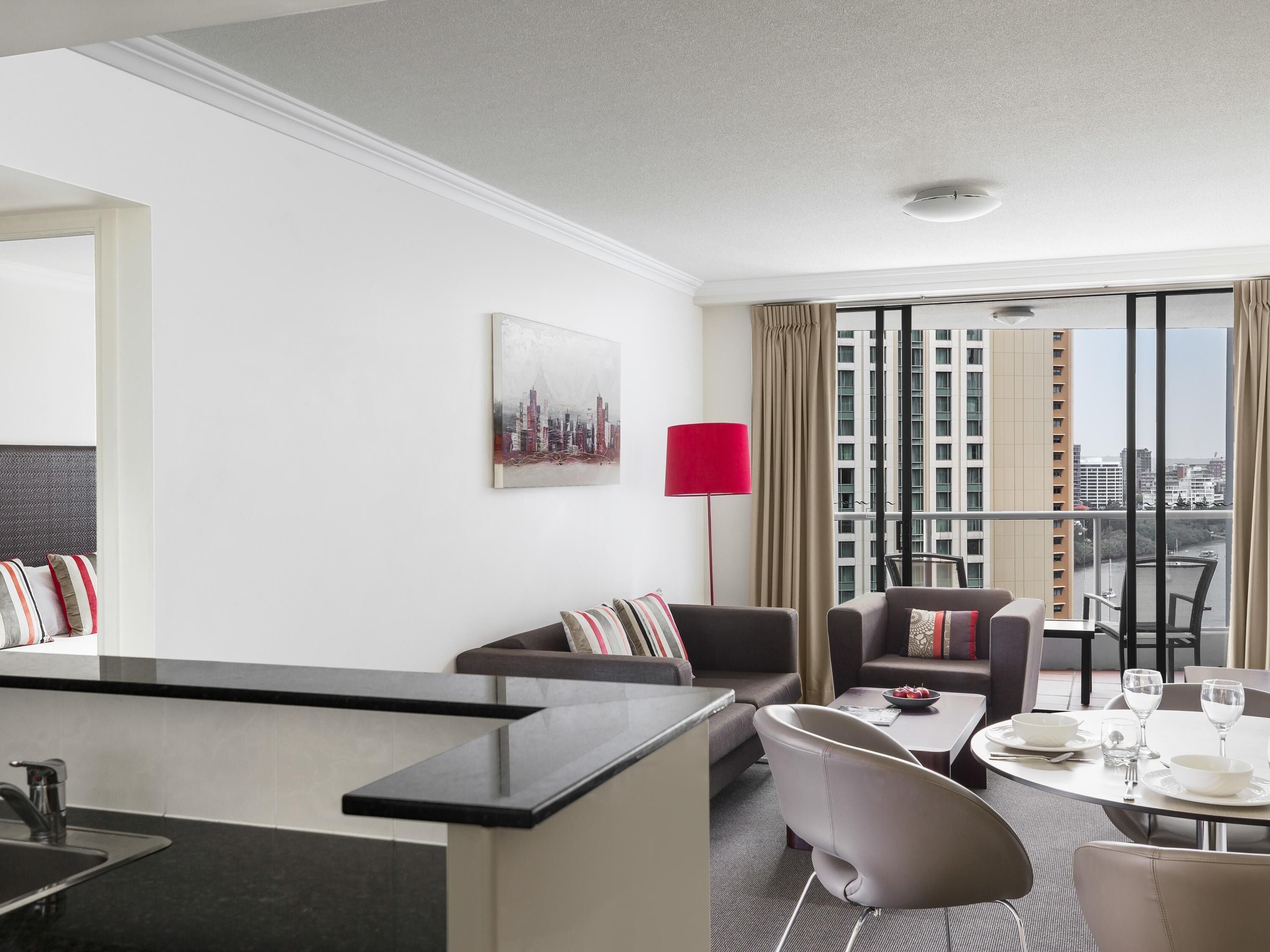Ein modernes Hotelzimmer mit Essbereich, Blick auf die Stadt und einer roten Lampe.