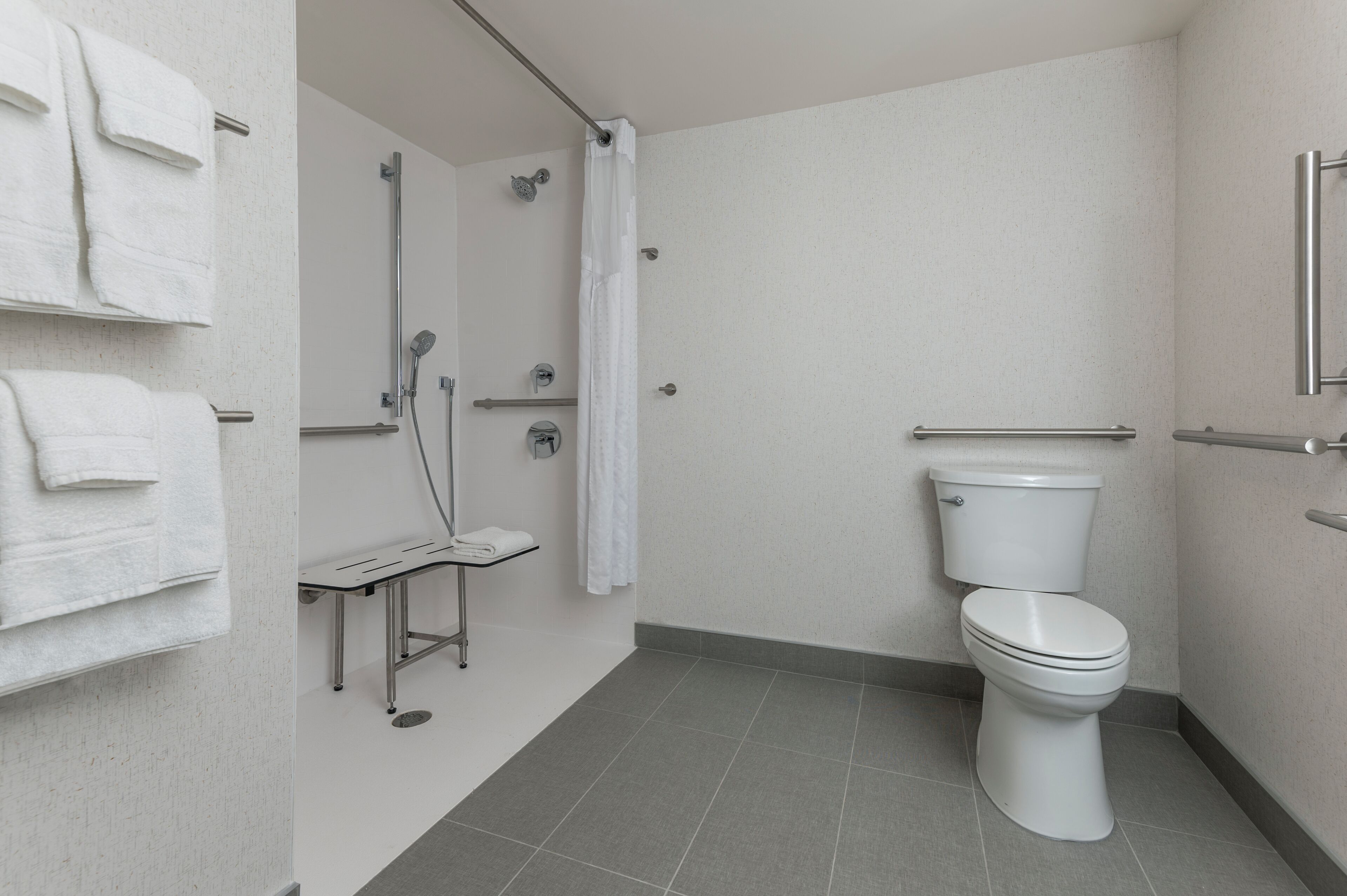 A bathroom with a toilet, shower, and towel rack.
