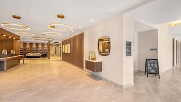 Un vestíbulo de hotel con mostrador de recepción, zona de estar y un espejo montado en la pared.