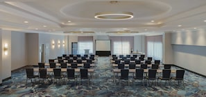 Una sala de conferencias con una gran mesa, varias sillas y un atril.