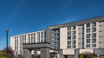A modern hotel building with a prominent entrance and a covered walkway.