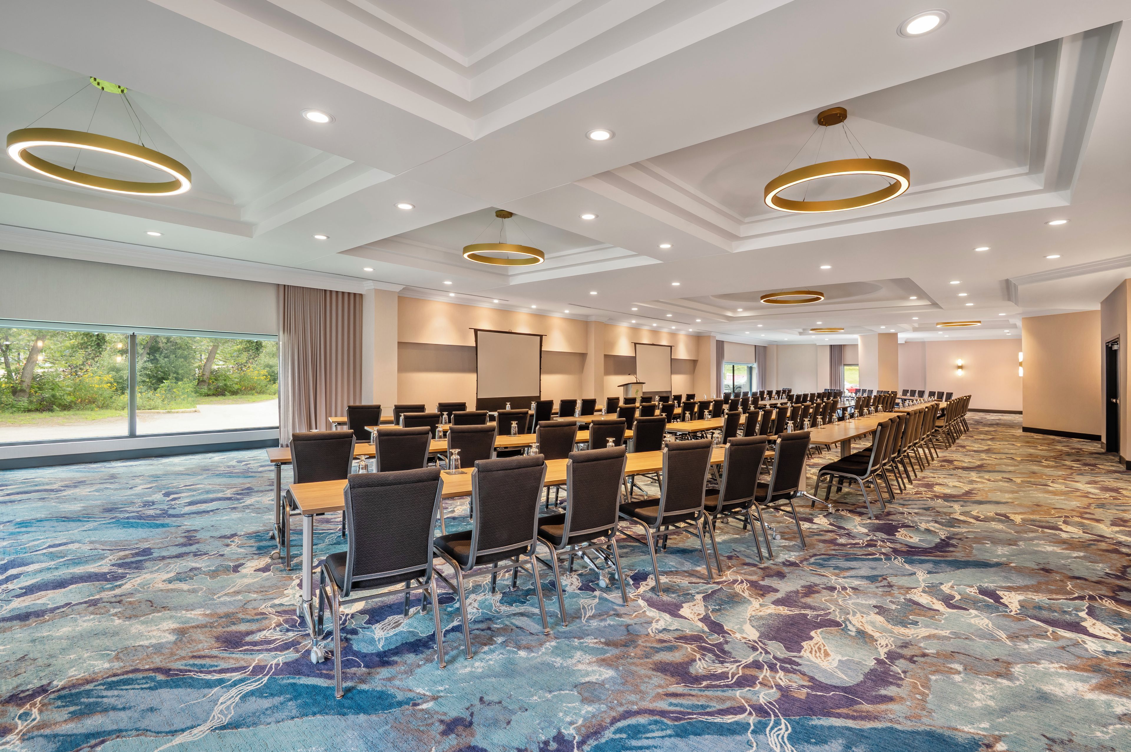 Un salón de conferencias con una larga mesa, sillas y una alfombra estampada.