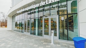 Ein modernes Gebäude mit großen Glasfenstern und einem Schild mit der Aufschrift 'Complexe aquatique de Laval'.