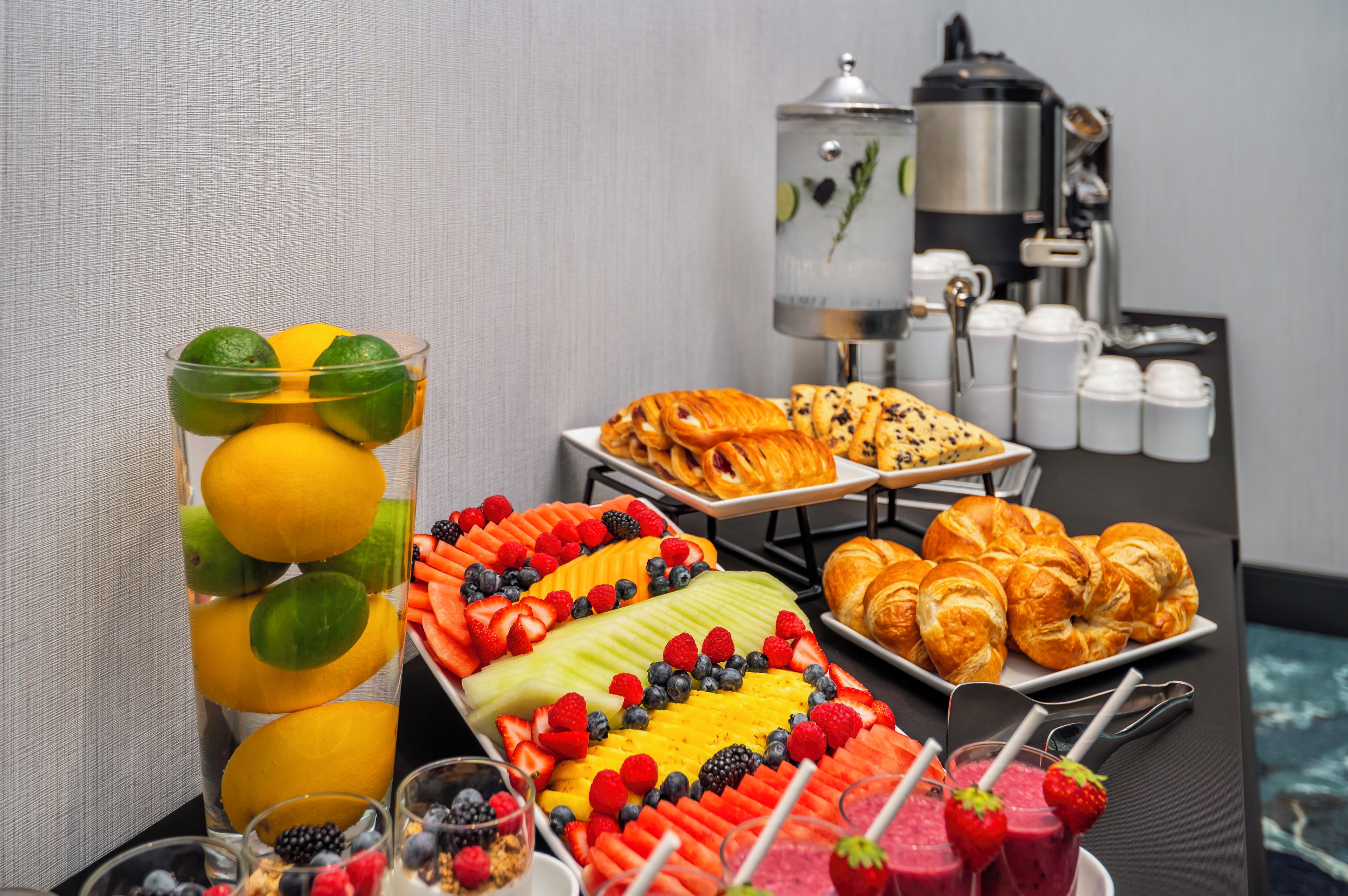Een ontbijtbuffet met fruit, gebak en drankjes.