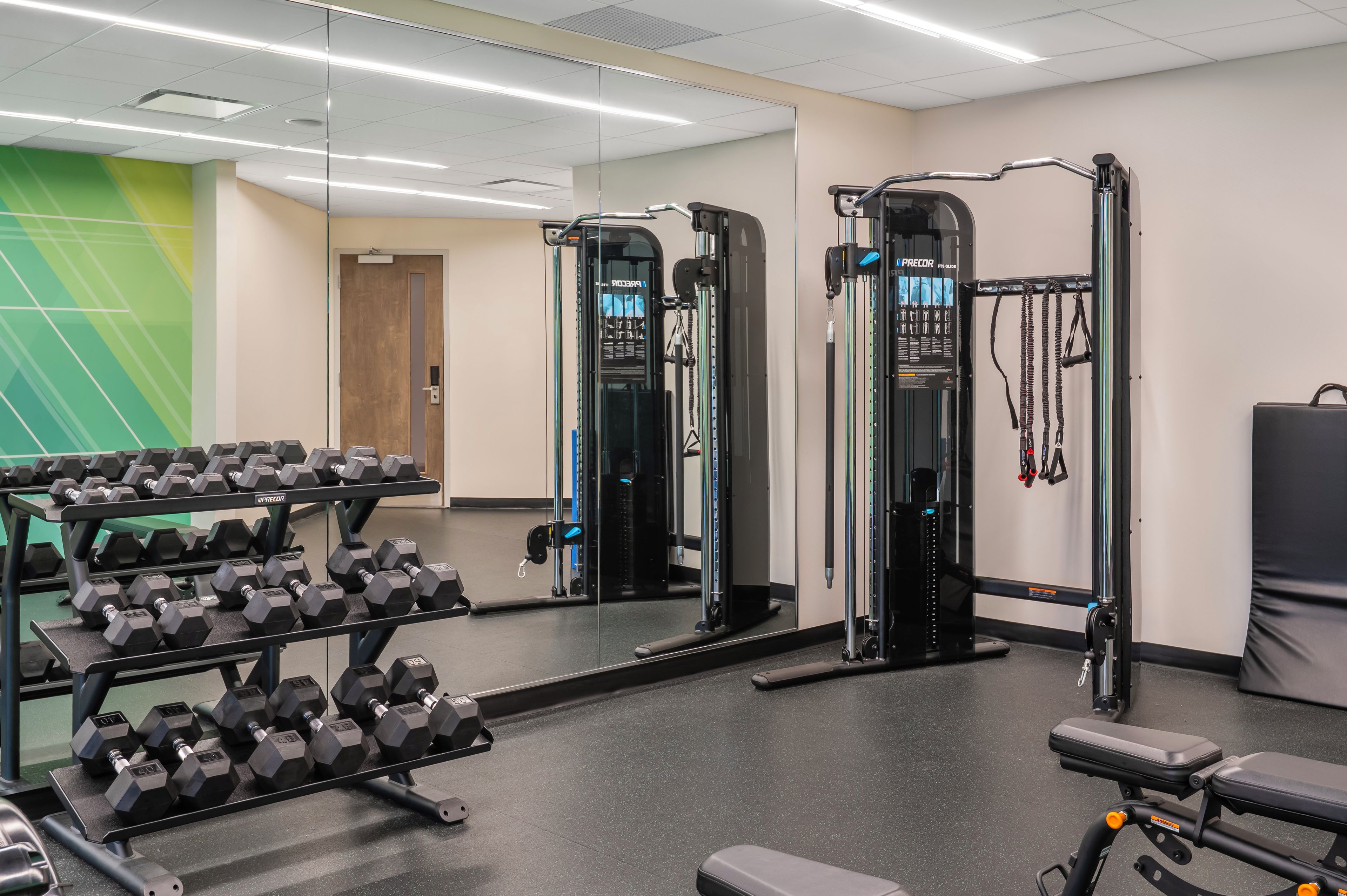 Ein Fitnessstudio mit Krafttrainingsgeräten, Kurzhanteln und Trainingsmaschinen.