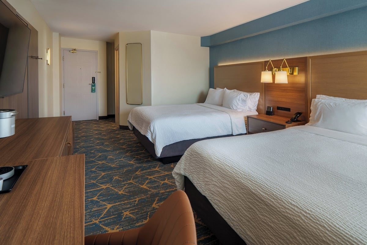 Une chambre d’hôtel avec deux lits, un bureau, une télévision et un minibar.