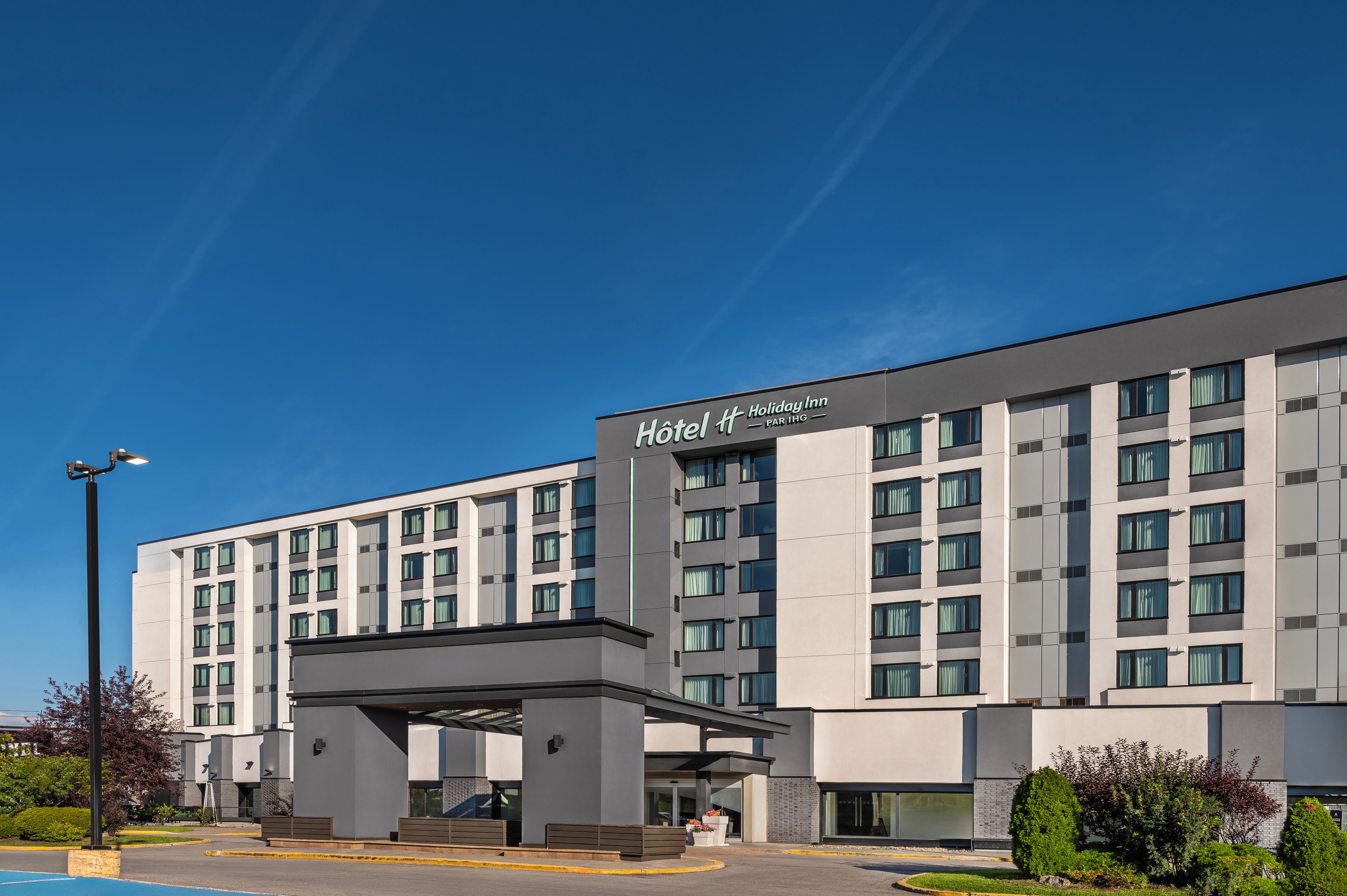 A modern hotel building with a prominent entrance and a covered walkway.