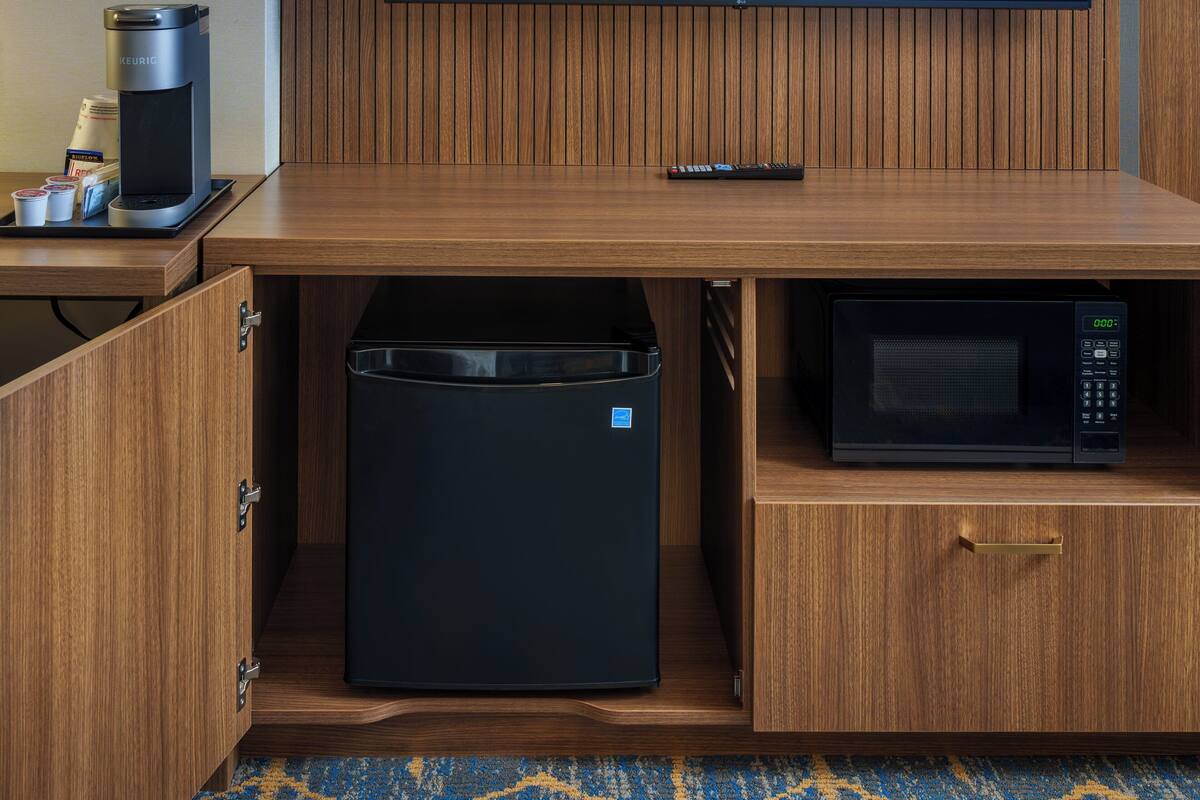 A compact kitchenette with a coffee maker, microwave, and a small refrigerator.