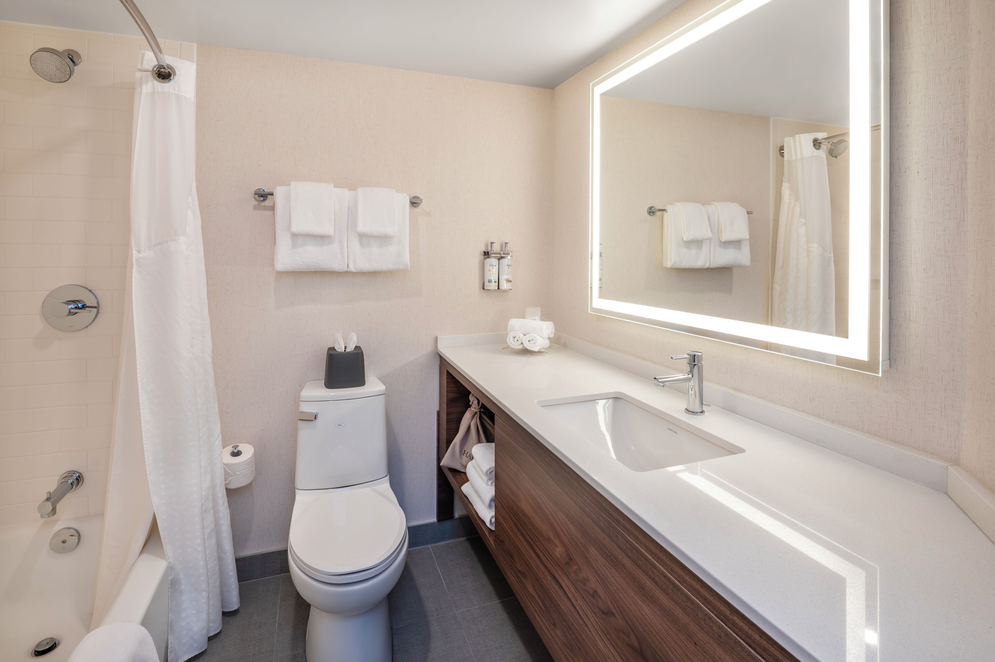 A modern bathroom with a shower, toilet, sink, and a large mirror.