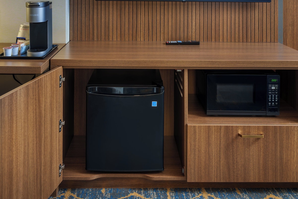 Una kitchenette compacta con cafetera, microondas y un refrigerador pequeño.