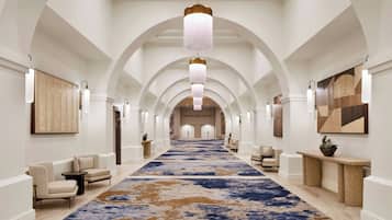 A hotel lobby with a long corridor, arched ceiling, and a large blue and brown patterned carpet.