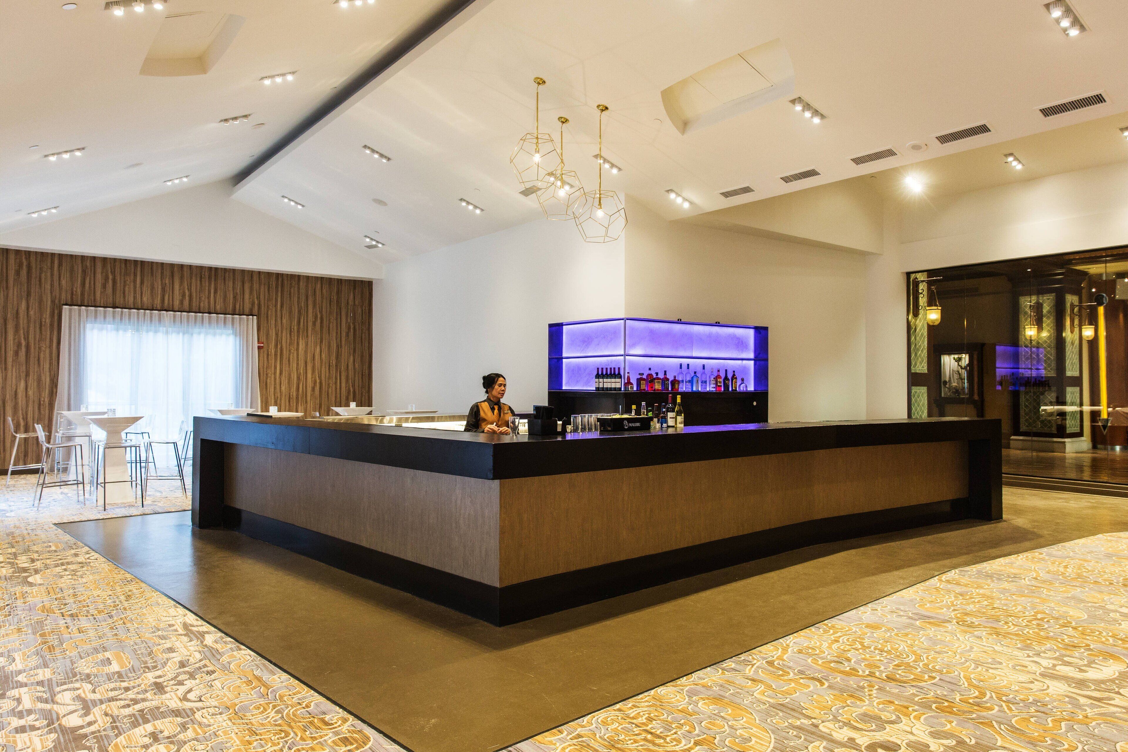 Un rebedor d'hotel modern amb taulell de recepció, zona de bar i seients.