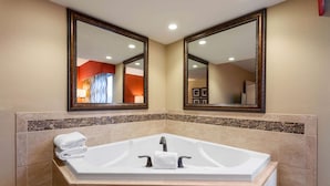 A modern bathroom with a large bathtub, two mirrors, and a tiled backsplash.