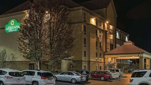 A hotel with a sign reading "La Quinta Inn & Suites." There are multiple parked cars in front of the building.